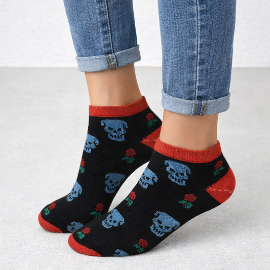 Black Ankle No show socks with blue skulls and red accents worn with blue jeans on a light gray background