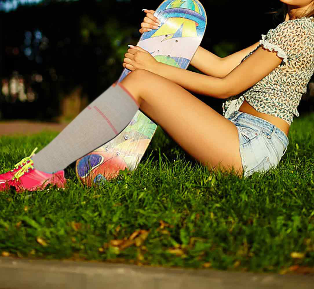 Woman standing comfortably while wearing knee-high compression socks for leg support.