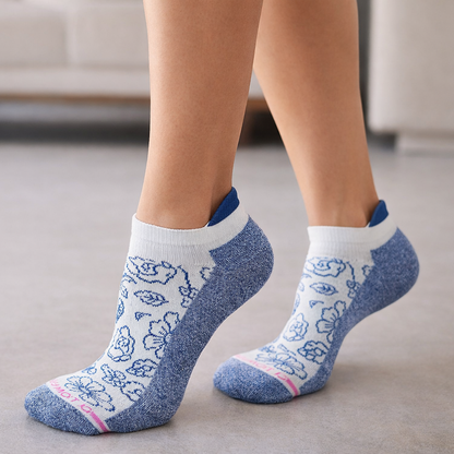 White ankle Compression socks with blue floral patterns worn by a person indoors.