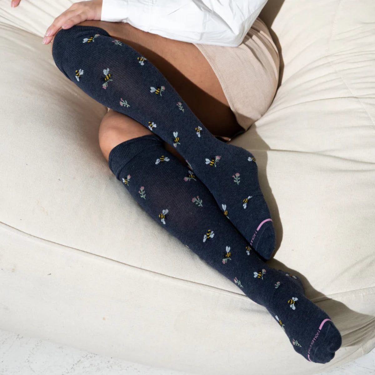 Woman wearing knee high compression socks with floral bee pattern for everyday comfort