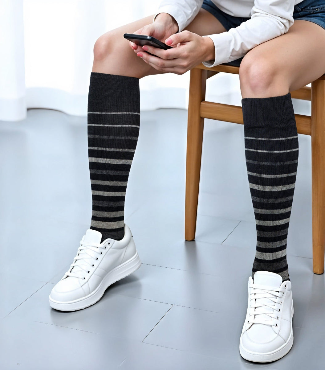 Woman wearing striped knee-high compression socks for circulation support and reduced leg fatigue
